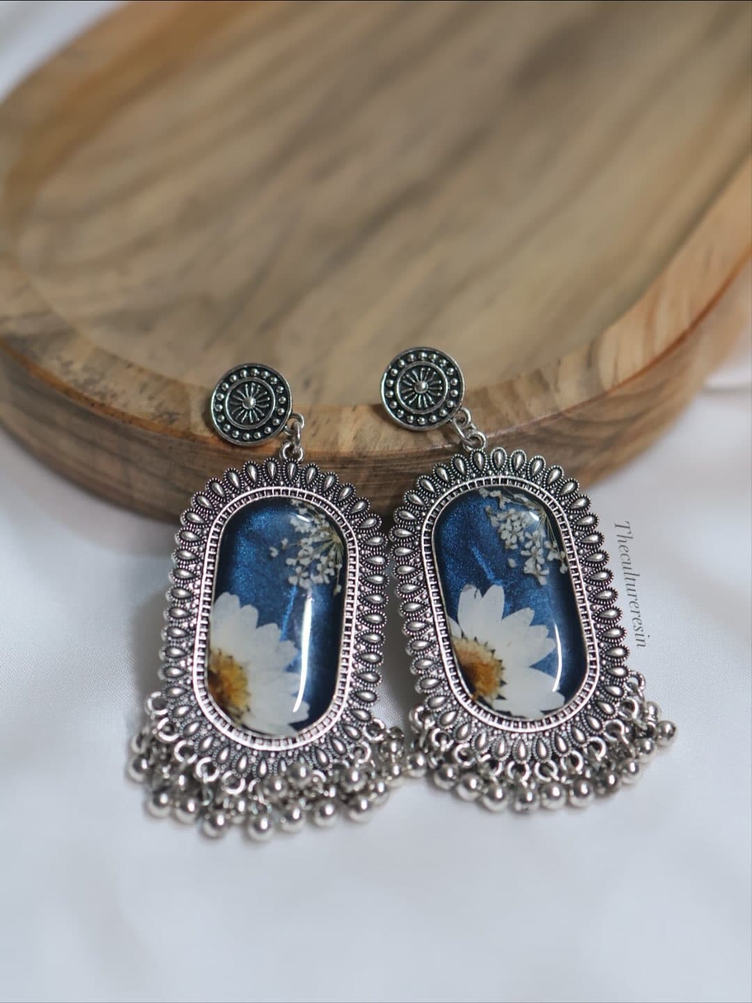 Pair of oxidised silver drop earrings with bead fringe, each set with a deep blue resin panel holding a pressed white daisy