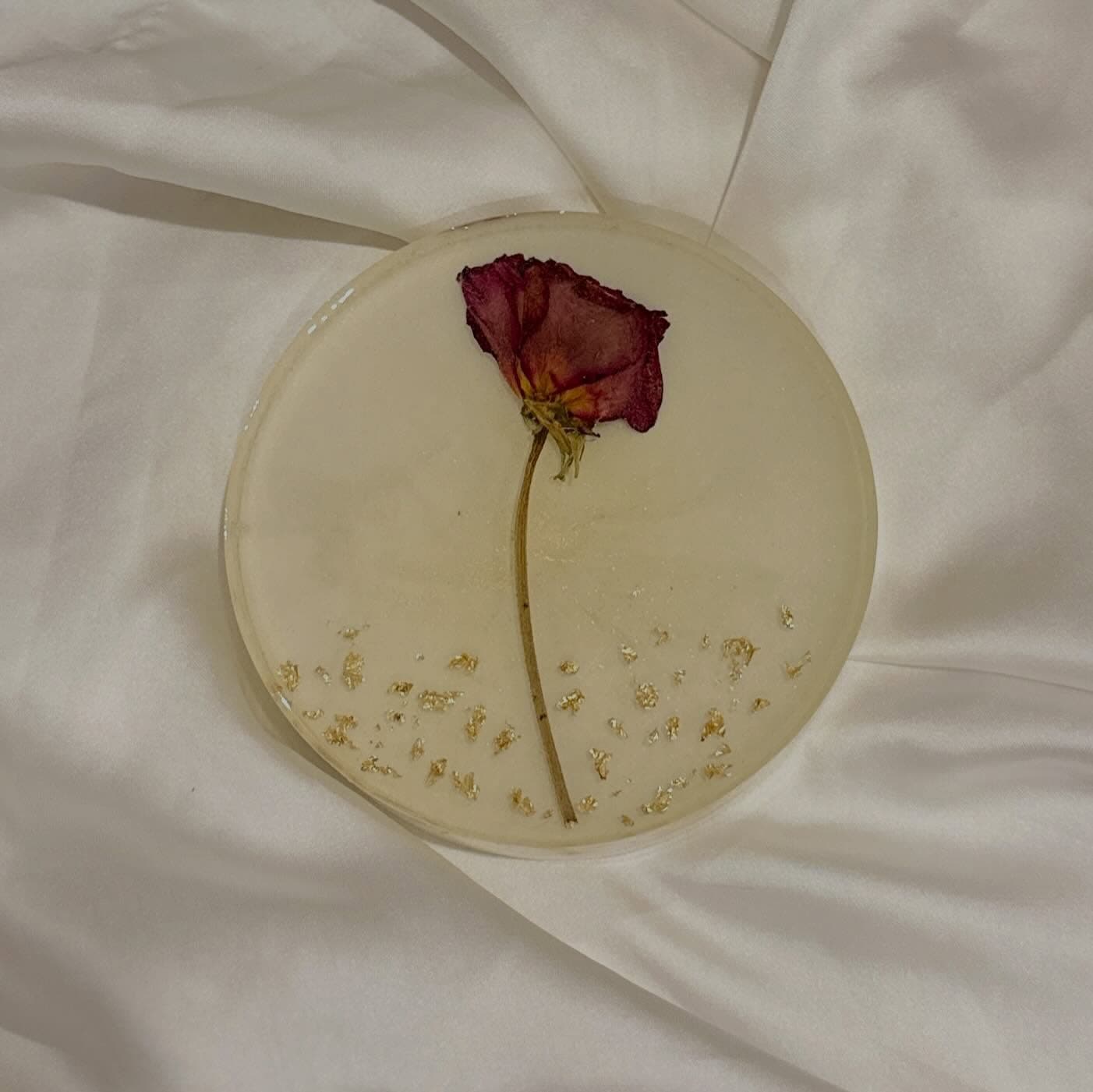 Milky translucent resin disc holding a single dried red rose, the surface still soft and clouded